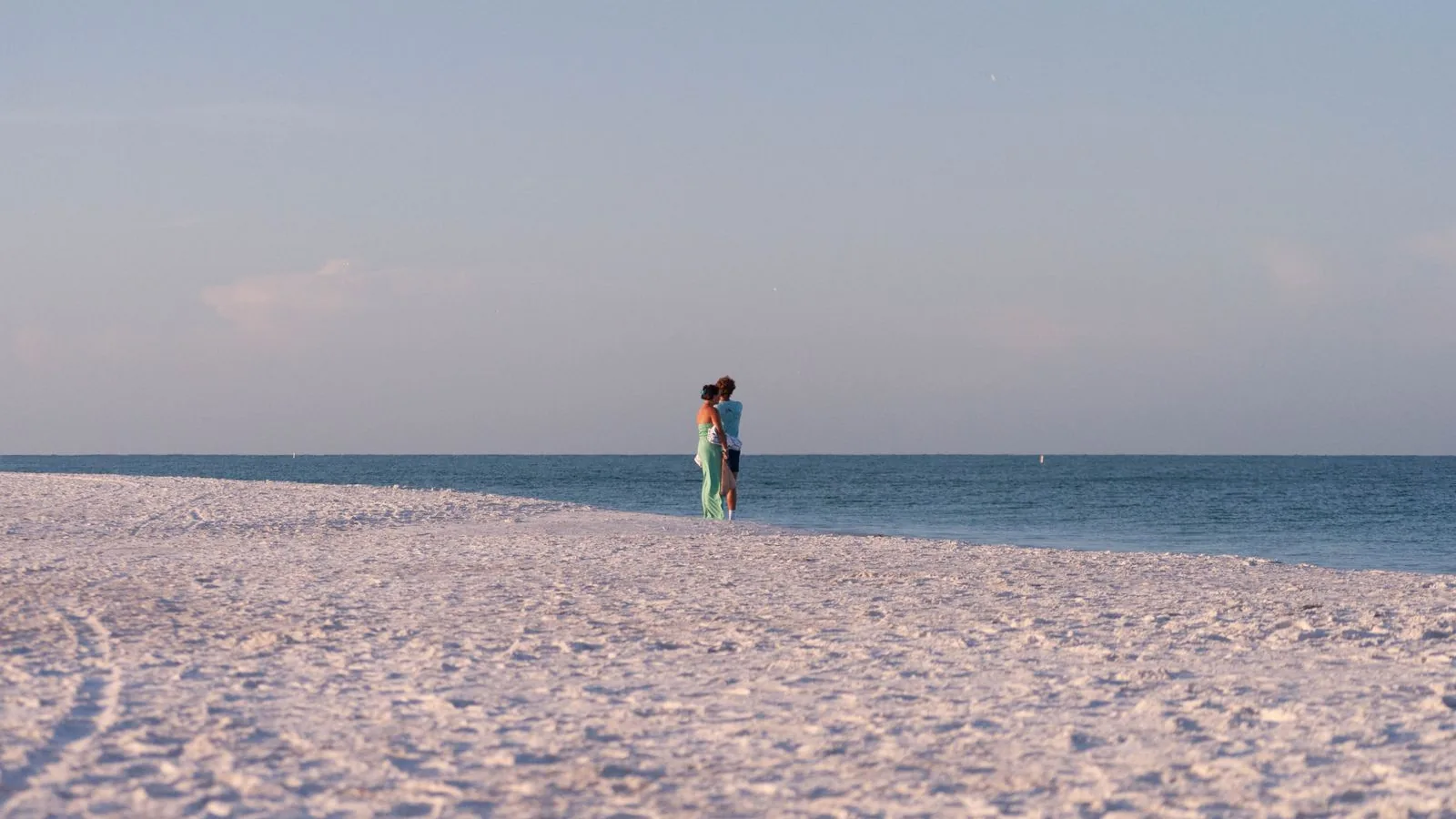 Una pareja pasea por una tranquila playa mediterránea mientras se plantea un tratamiento de IA en Chipre